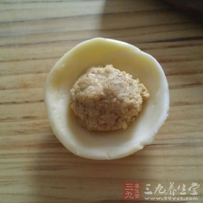 取一个饼皮，按压成圆饼，将五仁馅放在上面