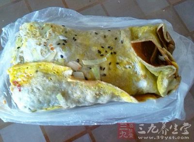 然后把饼翻面，在上面抹上面酱和辣椒酱，再放上油条和香菜、葱即可